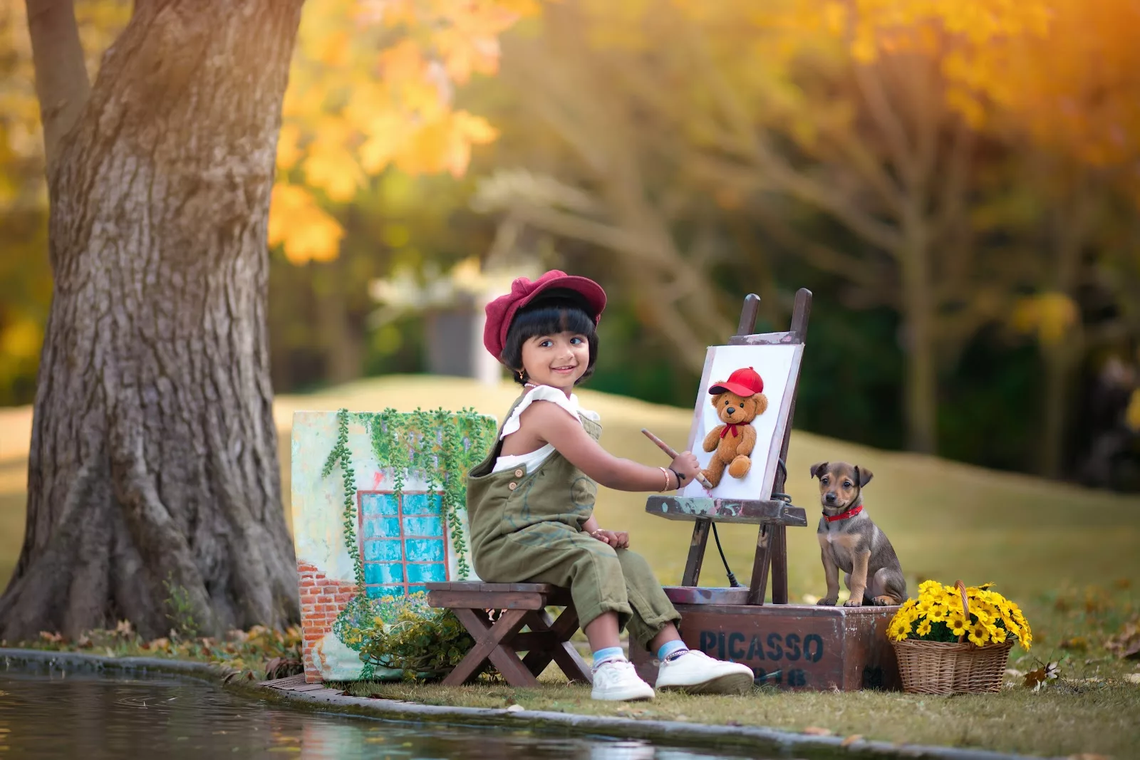 Young child painting beside an easel in a garden