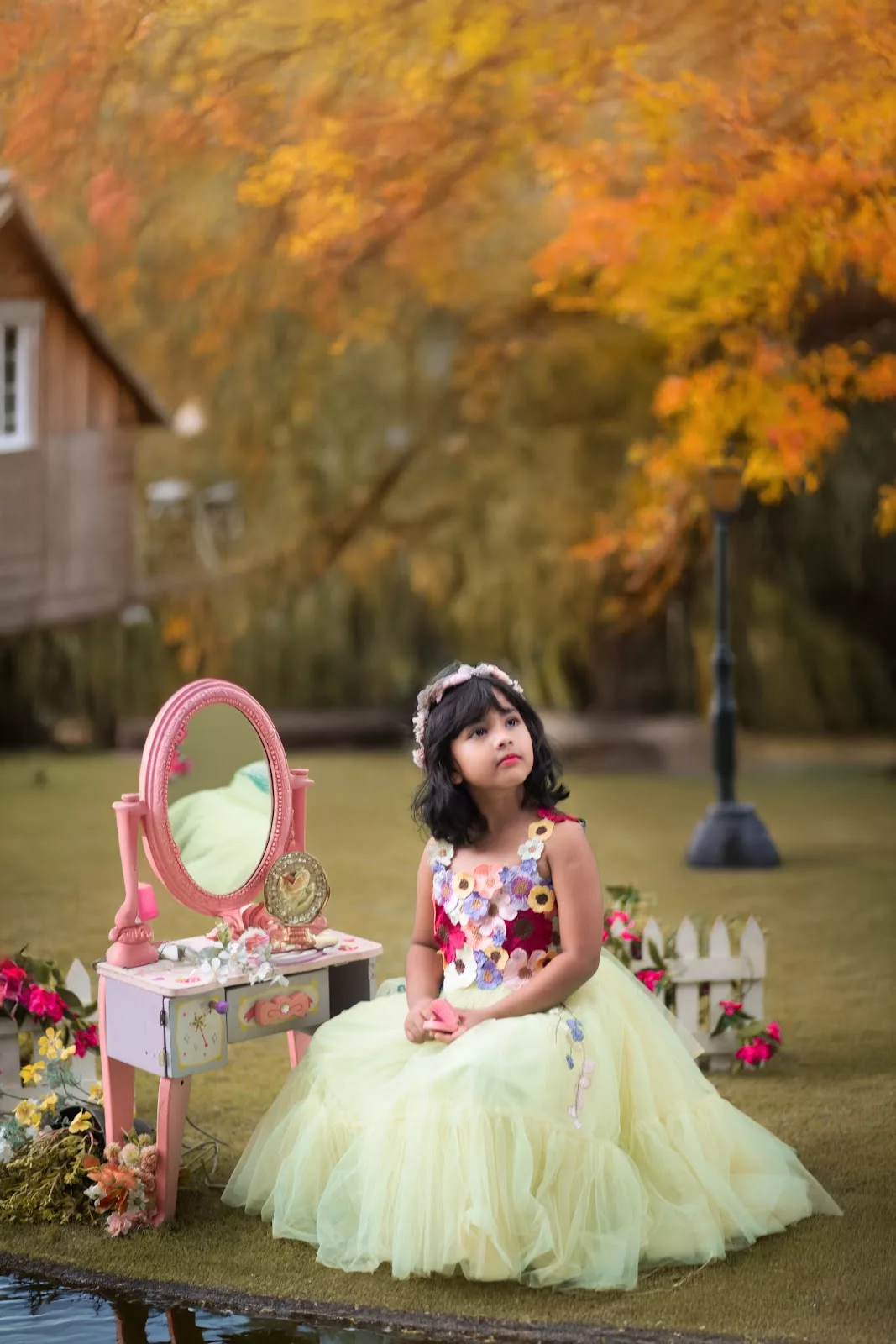 Young girl in a pale flower dress beside a dressing table