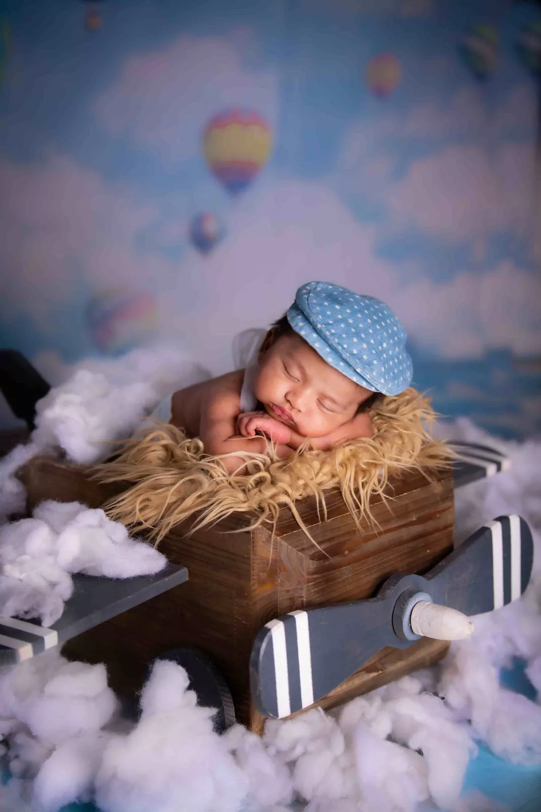 Newborn sleeping in a wooden aeroplane prop