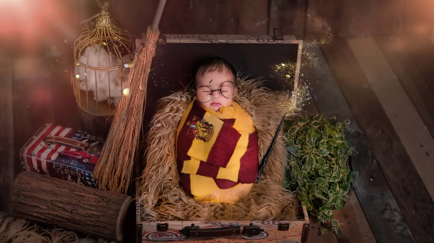 Newborn styled as a tiny wizard in a suitcase