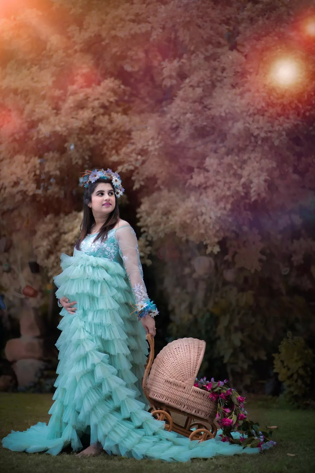 Expectant mother in an aqua gown beside a vintage pram